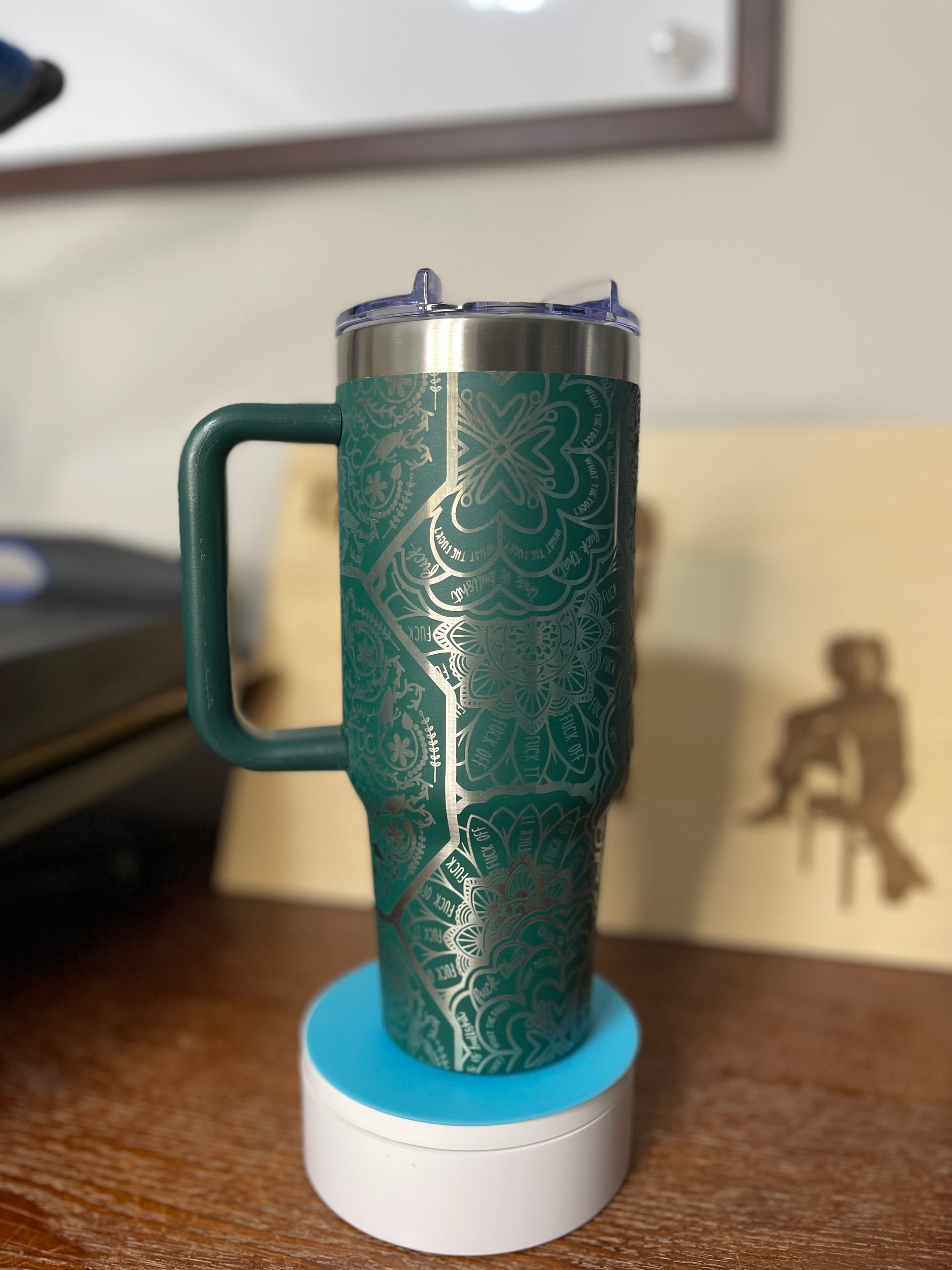 Green thermos with handle on a white base against a blurred background